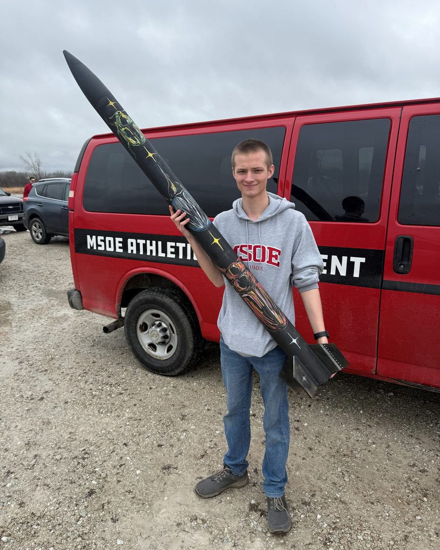 Ari Scheuer holding a high power rocket at a launch site