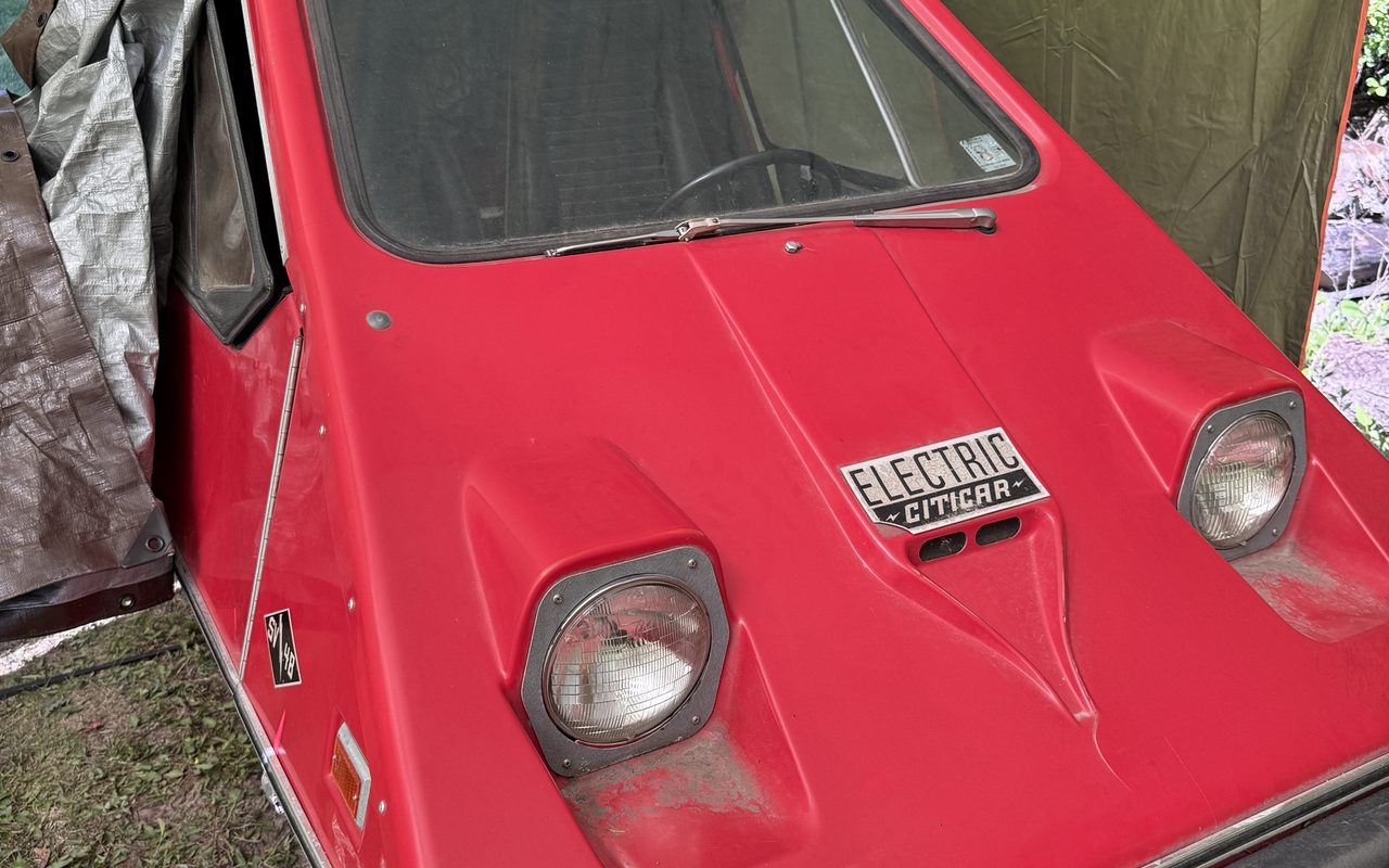 Red 1972 Sebring-Vanguard Citicar parked under a canopy